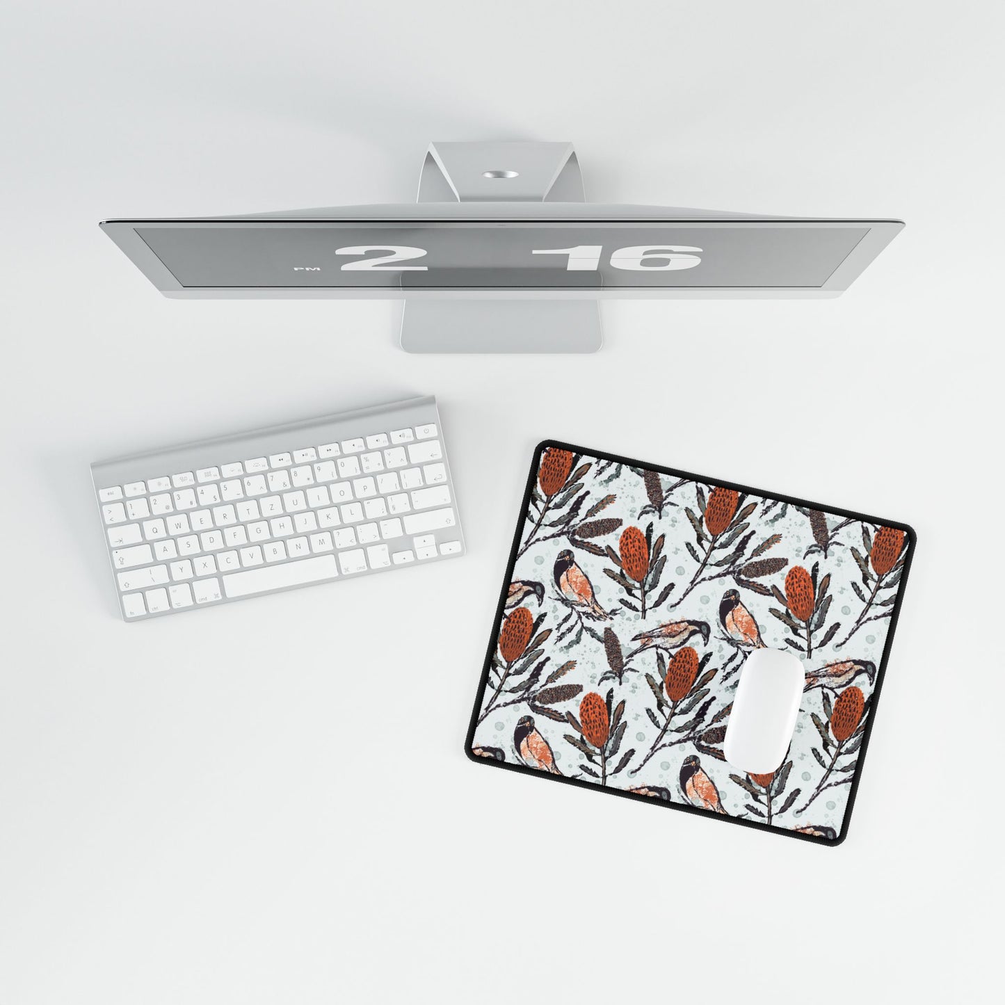 Desk setup with a computer, keyboard, mouse, and decorative mouse pad. Mouse pad shows hand drawn artwork of Australian honey eating birds