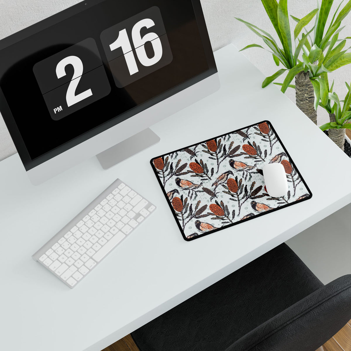 Desk setup with a computer, keyboard, mouse, and decorative mouse pad. Mouse pad shows hand drawn artwork of Australian honey eating birds