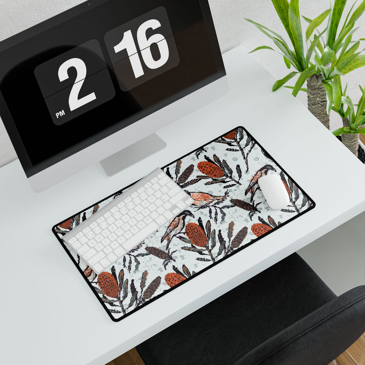 Desk setup with a computer, keyboard, mouse, and decorative mouse pad. Mouse pad shows hand drawn artwork of Australian honey eating birds